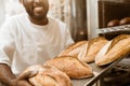 cropped shot of smiling african american baker with tray of fresh loaves of bread Royalty Free Stock Photo