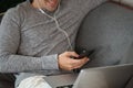 Smiling man using smart phone and laptop computer on sofa. Royalty Free Stock Photo