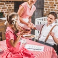 cropped shot of smiling parents looking at cute daughter eating toast with jam for breakfast 1950s Royalty Free Stock Photo