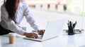 Smiling young female employee working with computer laptop at white office desk near window. Royalty Free Stock Photo