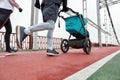 Cropped shot of sportive couple, young parents running together with a stroller on a bridge in the city on a cloudy day Royalty Free Stock Photo