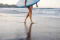 cropped shot of sportswoman in swimming suit with blue surfing board walking