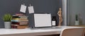 Study table with mock up laptop, stack of books, notepad and decorations on white table Royalty Free Stock Photo