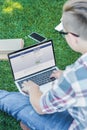 cropped shot of teenager using laptop with facebook website while sitting in park