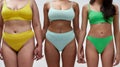 Cropped shot of three women with different body shapes in colorful underwear holding hands, supporting each other