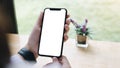 Cropped shot top view of woman hands using smartphone mockup at the white office desk. Blank screen mobile phone for graphic