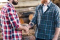 cropped shot of two bearded lumberjacks in checkered shirts shaking hands