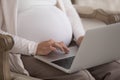 Cropped shot pregnant woman sit on armchair with laptop Royalty Free Stock Photo