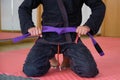 Cropped shot of an unrecognizable man tying a purple Brazilian Jiu-Jitsu belt.