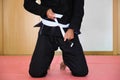 Cropped shot of an unrecognizable man tying a white Brazilian Jiu-Jitsu belt. Royalty Free Stock Photo