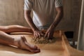 Cropped shot of unrecognizable massage practitioner male mixing heated sand on massage table for scrubbing treatment in