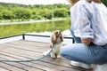 Woman with straw hat while sitting on the pier with her puppy at lake Royalty Free Stock Photo