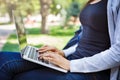 Cropped shot of young brunette woman typing. Working with laptop in the park Royalty Free Stock Photo