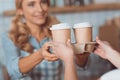 cropped shot of waitress and buyer holding coffee to go in paper