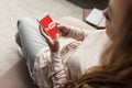 cropped shot of woman on couch using smartphone with youtube logo Royalty Free Stock Photo
