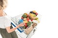 cropped shot of woman holding credit card and shopping trolley with grocery bags