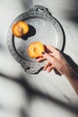cropped shot of woman holding peach piece on metal tray on light