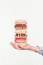 cropped shot of woman holding stack of tasty doughnuts isolated on white