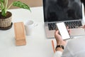 Cropped shot woman holding and using mockup mobile phone with blank white screen and laptop. Royalty Free Stock Photo