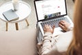 cropped shot of woman at home sitting on couch and using laptop with airbnb website