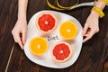 cropped shot of woman with measuring tape on hand holding plate with halved citrus fruits and diet inscription