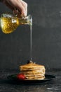 cropped shot of woman pouring maple syrup onto stack of freshly