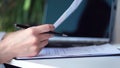 Cropped shot of woman's hand writing something while using laptop at desk. close up, on a white desktop there is a Royalty Free Stock Photo