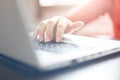 Cropped shot of woman`s hands typing on keyboard of laptop computer, finishing a chapter of her book while sitting at wooden table