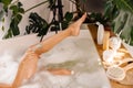 Cropped shot of woman shaving her legs with disposable shaving razor while taking bath. Body care cosmetics on wooden Royalty Free Stock Photo