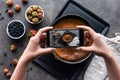 cropped shot of woman taking picture of homemade pie on dark