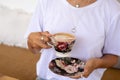 cropped shot of Woman in white shirt holding cup of hot cappuccino on wooden table, top view. Royalty Free Stock Photo