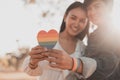 Cropped shot of women LGBT lesbian couple hands holding a heart shape painted like a rainbow pride. LGBT equal rights concept