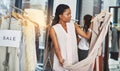 I wonder if they have this in my size. Cropped shot of a woman looking at dresses on a rail with a sign that reads sale. Royalty Free Stock Photo