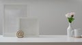 Cropped shot of workspace with mock up frames, coffee cup and decorations on white wooden table