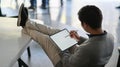 Cropped shot of a young businessman using a tablet. He sat on a chair and his feet rested on the table Royalty Free Stock Photo