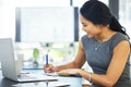 Putting plans into perspective and on paper. Cropped shot of a young businesswoman writing notes while working on a Royalty Free Stock Photo