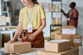 Cropped shot of young female manager of warehouse preparing parcels for sending