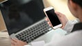 Cropped shot of a young female working with mock up laptop while looking on mock up smartphone. Royalty Free Stock Photo