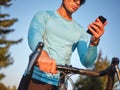 Cropped shot of young male biker wearing sportswear and glasses using smartphone, standing with his bike in park on a Royalty Free Stock Photo