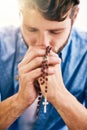 Putting his faith first. Cropped shot of a young man holding his rosary while praying. Royalty Free Stock Photo