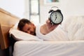 Time to face the day. Cropped shot of a young man holding up an alarm clock while waking up from bed at home. Royalty Free Stock Photo