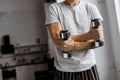 Cropped shot of young man in pajamas holding dumbbells Royalty Free Stock Photo