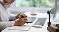 A young man sitting in front of computer and writing important ideas in a notebook. Royalty Free Stock Photo