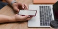 Cropped shot of young man using blank screen smartphone while working on his project with laptop Royalty Free Stock Photo