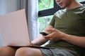 Young man using smart phone and laptop in living room. Royalty Free Stock Photo