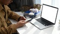 Cropped shot of young man working from home with laptop computer and using smart phone for social media. Royalty Free Stock Photo