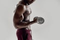 Cropped shot of young muscular african american man lifting weights, standing isolated over grey background. Sports Royalty Free Stock Photo