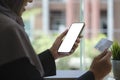 Cropped shot young muslim woman in hijab holding credit card and smart phone with blank screen. E-commerce, internet banking Royalty Free Stock Photo