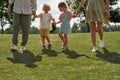 Cropped shot of young parents with two little kids holding hands, walking together outside in green summer park Royalty Free Stock Photo