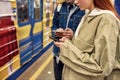 Cropped shot of young people using smartphones while standing at the subway metro station. Couple of teenagers using Royalty Free Stock Photo